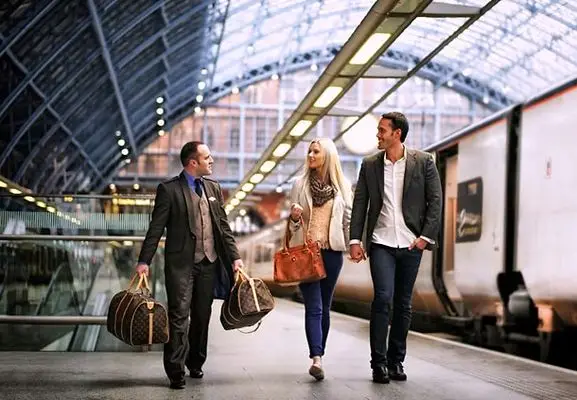 Chauffeur privé aéroport Courchevel portant les bagages d'un couple sur le quai de la gare